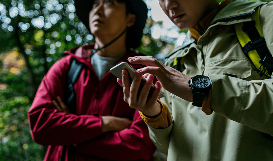 山の中スマホを使って位置や地図の確認する登山家
